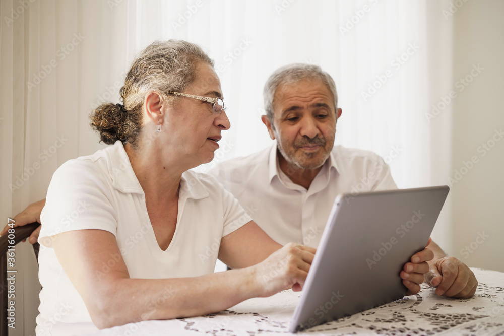 The elderly couple trying to use the tablet show each other something on the screen. old couple is trying to talk to their grandchildren. elders enjoying with benefits of technology The elderly couple trying to use the tablet show each other something on the screen. old couple is trying to talk to their grandchildren. elders enjoying with benefits of technology