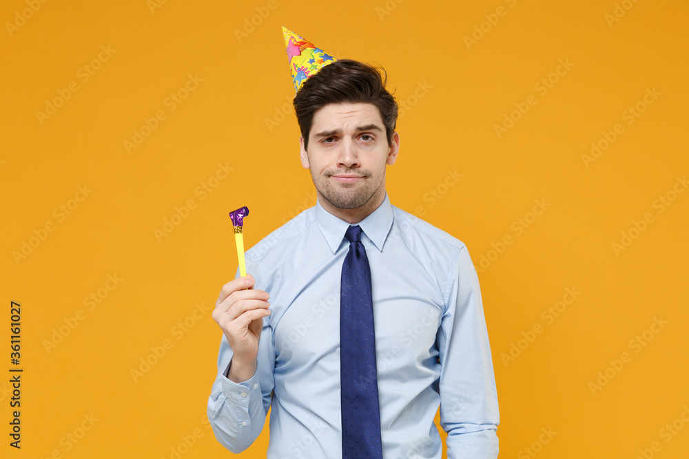 Displeased young business man in classic blue shirt tie birthday hat posing isolated on yellow background studio portrait. Achievement career wealth business concept. Mock up copy space. Hold pipe.