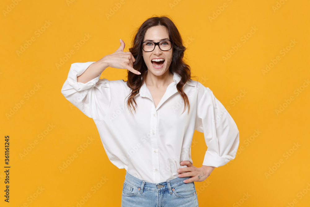Excited young brunette business woman in white shirt glasses isolated on yellow background. Achievement career wealth business concept. Mock up copy space. Doing phone gesture like says call me back. Excited young brunette business woman in white shirt glasses isolated on yellow background. Achievement career wealth business concept. Mock up copy space. Doing phone gesture like says call me back.