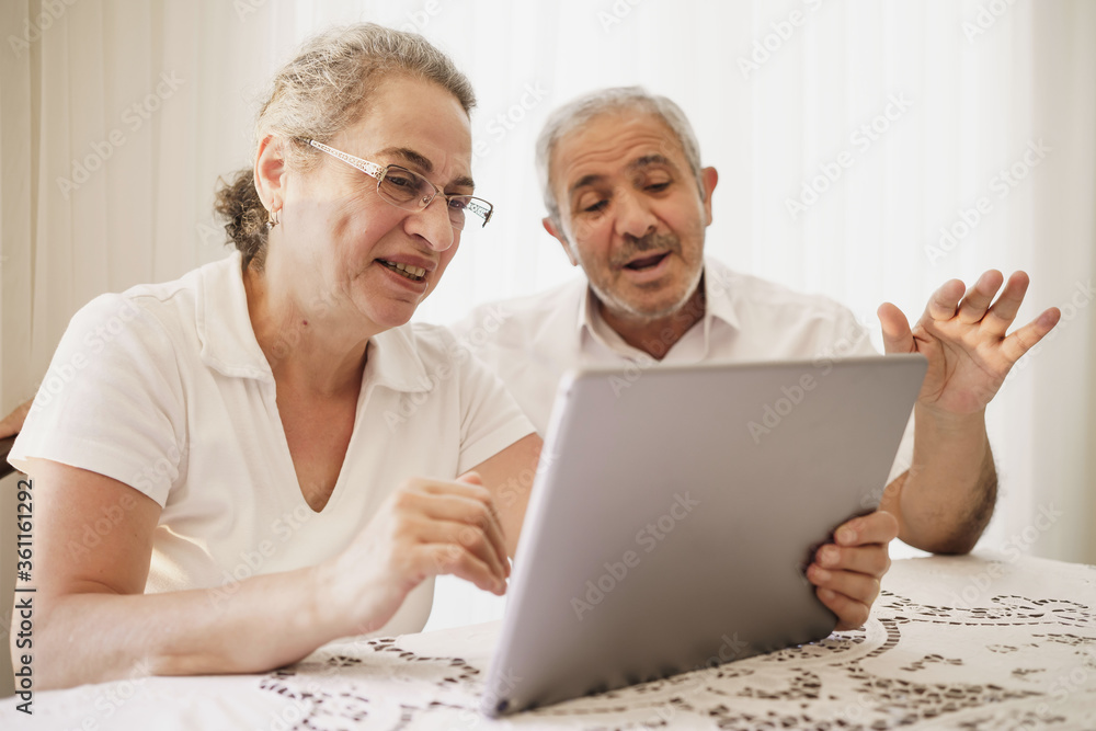 The elderly couple trying to use the tablet show each other something on the screen. old couple is trying to talk to their grandchildren. elders enjoying with benefits of technology The elderly couple trying to use the tablet show each other something on the screen. old couple is trying to talk to their grandchildren. elders enjoying with benefits of technology
