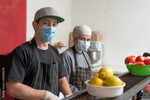 mujer y hombres jovenes cocinando con guantes y barbijo para precaucion del covid-19 photo