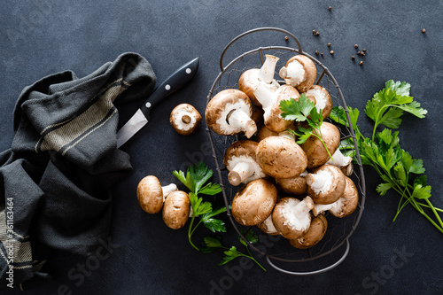 Raw mushrooms champignons on black background, cooking fresh champignons.