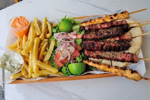 Cypriot style mixed souvlaki and gyros plate with fries, dips, fresh salad and lime served on a pita bread in Cyprus photo