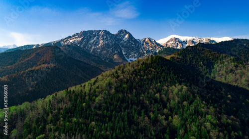 Aerial view of green hills and mountains covered with snow in summer or spring. Giewont mountain massif in the Tatra Mountains of Poland and panorama of Zakopane