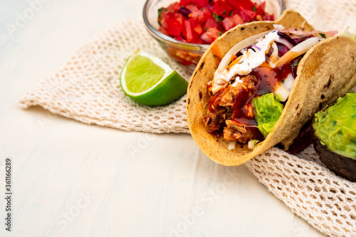 Mexican traditional authentic homemade tacos with pulled pork beef chili con carne serve with tomato salad and avocado guacamole and dip sauce