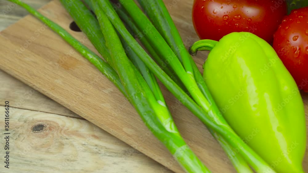 On the cutting Board, on the kitchen table are onions, lettuce, green peppers, tomatoes and cucumbers, Panorama in motion. Camera movement. On the cutting Board, on the kitchen table are onions, lettuce, green peppers, tomatoes and cucumbers, Panorama in motion. Camera movement.