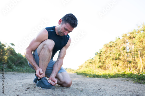 man doing shoe laces up on a run
