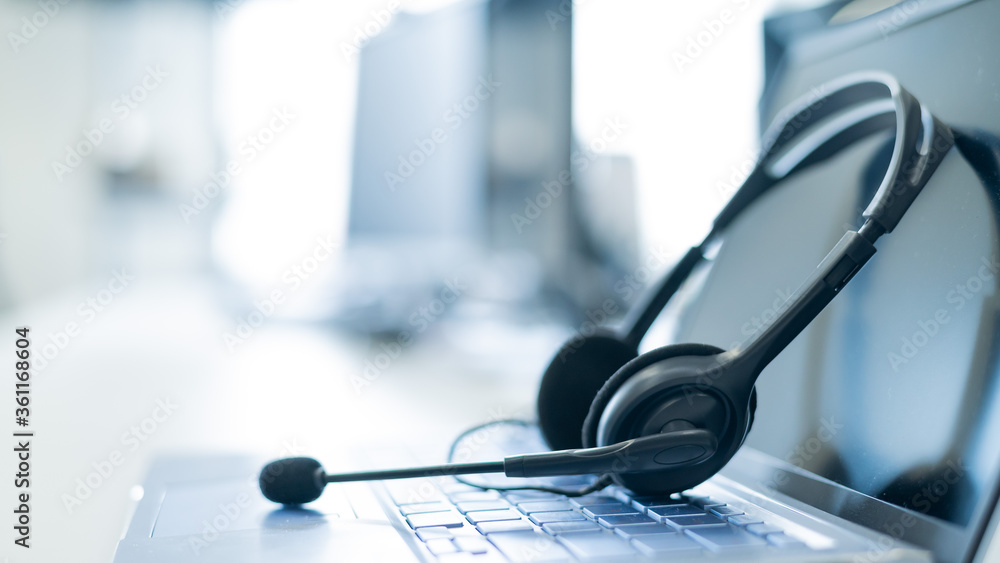 Call center operator desktop. Close-up of a headset on a laptop. Help desk.  Workplace of a support service employee. Headphones with a microphone for  voip on a computer keyboard. Stock Photo |