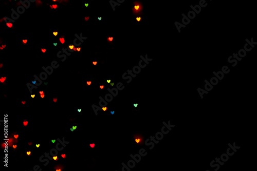 Little colorful bokeh hearts on black background. For Valentine's Day celebrations