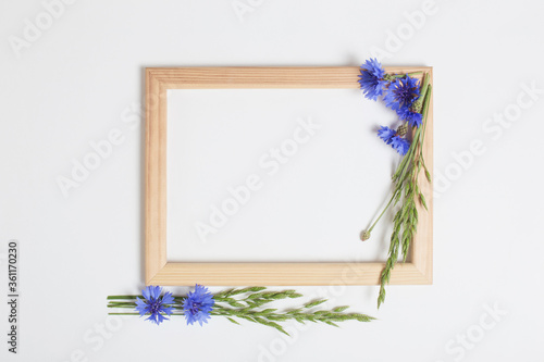 blue cornflowers and wooden frame on white background