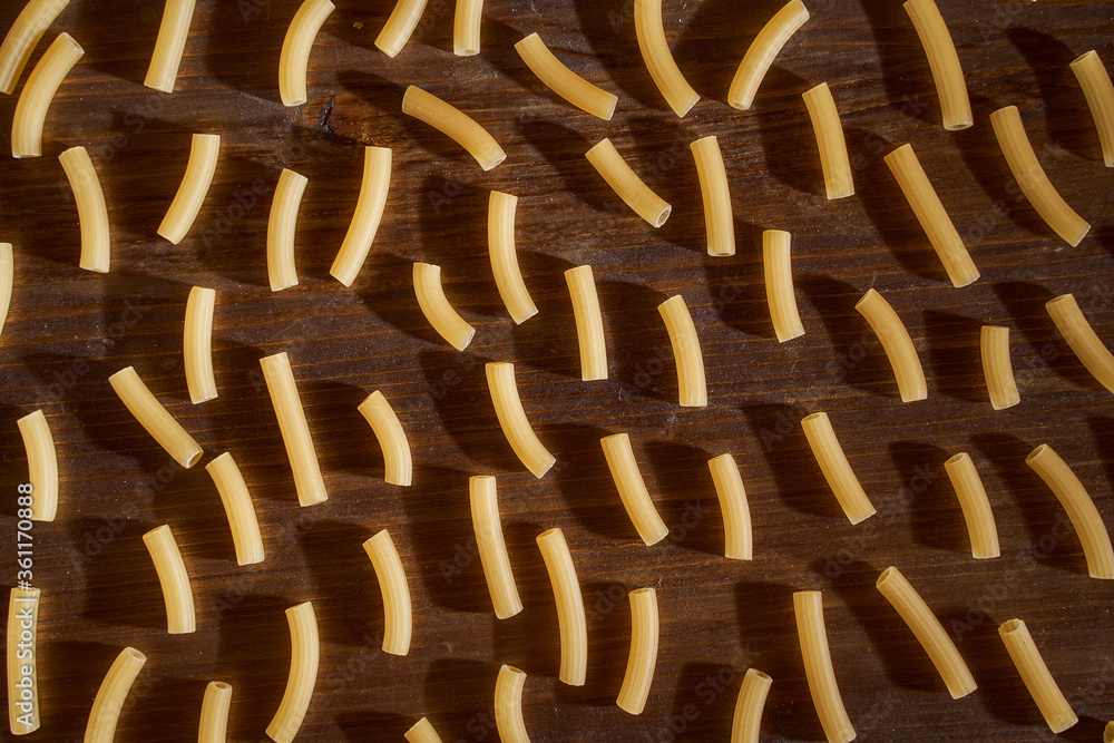 Fototapeta premium a lot of Yellow pasta lies on a brown table. Close-up. Top view.
