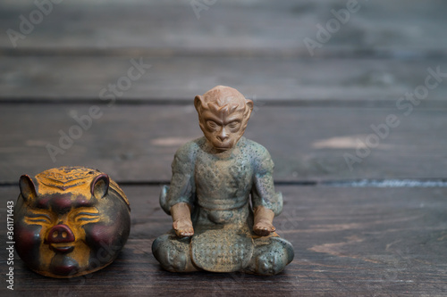 Different tea decorative chinese figurines: king of monkey and pig on dark wooden table