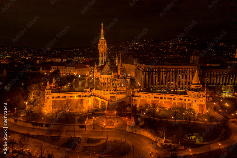 Aerial drone shot of Matthias Church with lights on Buda Hill in Budapest evening