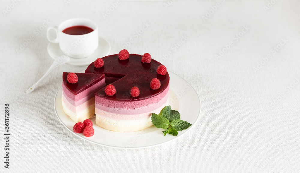 Composition on a light background, a dish with mousse cake and a Cup of red tea karkade. The concept of proper dietary nutrition and cake day. Selective focus. Composition on a light background, a dish with mousse cake and a Cup of red tea karkade. The concept of proper dietary nutrition and cake day. Selective focus.