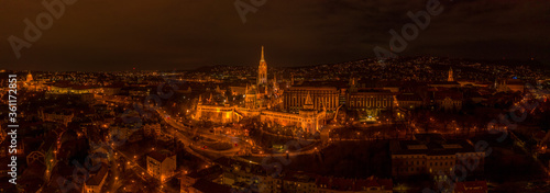 Panoramic aerial drone shot of Matthias Church with lights on Buda Hill in Budapest evening
