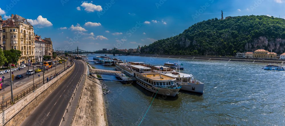 A panorama view across the River Danube in Budapest from the eastern shore to the Gellert Hill and Liberty Statue during summertime