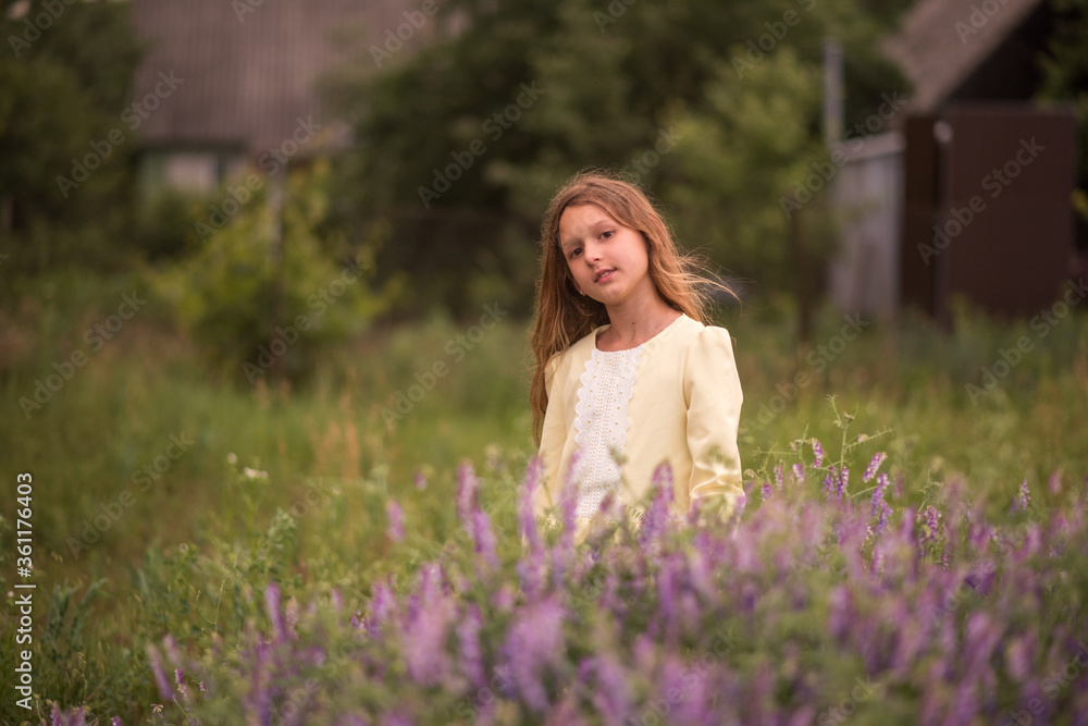 Beautiful girl at sunset in a field with purple flowers. Lavender. The child walks and travels. Rest and games. Long haired girl Beautiful girl at sunset in a field with purple flowers. Lavender. The child walks and travels. Rest and games. Long haired girl