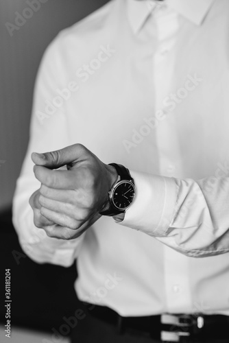 Stylish young man buttoning the cuff links on the sleeves. Style © Andrii
