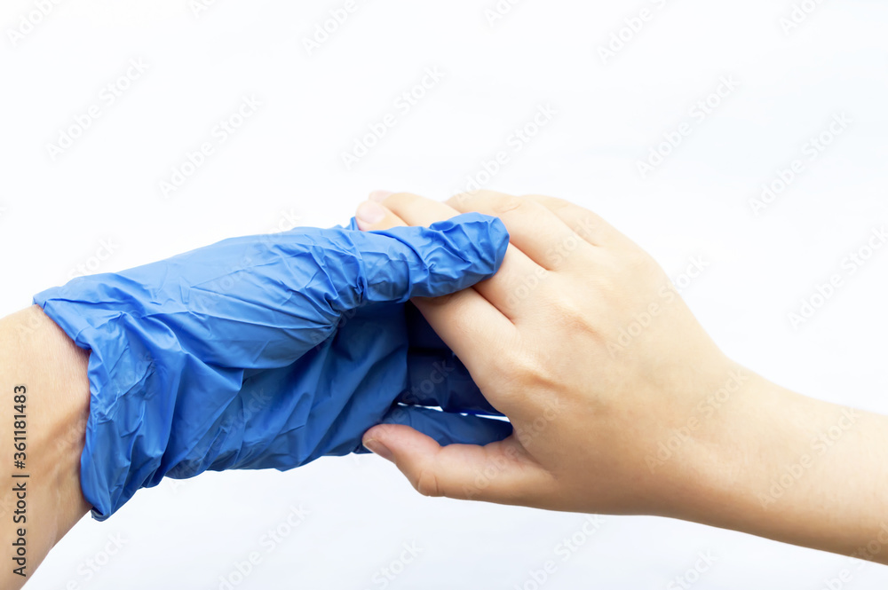 The hand of a man in blue sterile gloves greets the hand of a man without gloves on a white background. The concept of protection from viruses. Selective focus. The hand of a man in blue sterile gloves greets the hand of a man without gloves on a white background. The concept of protection from viruses. Selective focus.