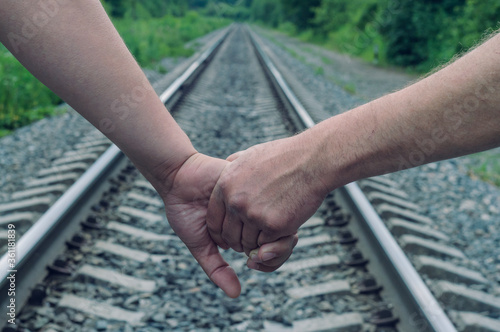 Two gay men holding hands on the background of the railway. Genesis between men. Rough hands hold each other. Gay couple