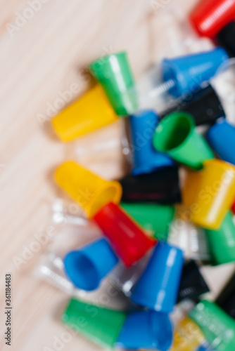 A large pile of multicolored plastic cups scattered on the floor with free space, out of focus. Pollution of the environment by human waste