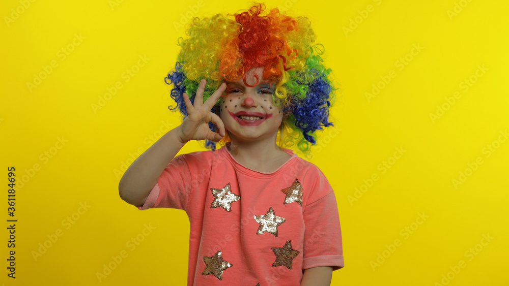 Little child girl clown in colorful wig making silly faces, having fun, smiling, dancing. Halloween Little child girl clown in colorful wig making silly faces, having fun, smiling, dancing. Halloween