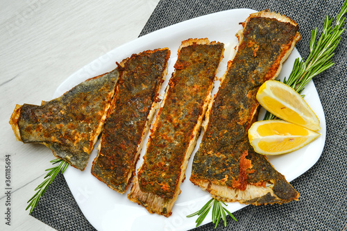 Canvastavla Top view of fried flounder cut on pieces served with lemon