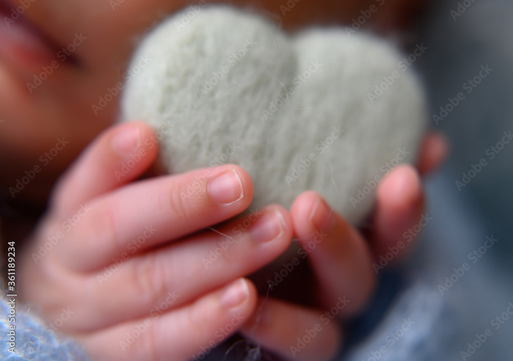 Detalhe das mãozinhas de um bebê segurando um coração Detalhe das mãozinhas de um bebê segurando um coração
