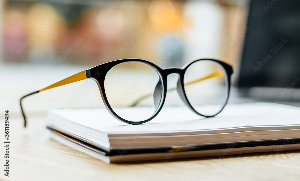 Glasses at the workplace in the office near the laptop and notepad. Business hours Glasses at the workplace in the office near the laptop and notepad. Business hours