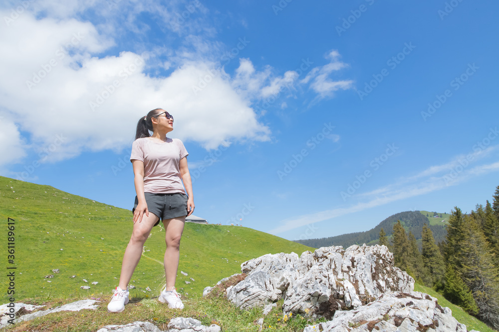 Beautiful Asian women with black hair and White skin wearing exercise clothes.she is standing Happy and smiling on the stone of the mountain, tourism of nature, Gantrischseeli at Switzerland,