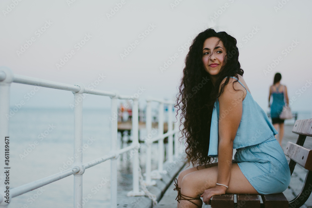 Woman sitting on pier bench and relaxing by the sea