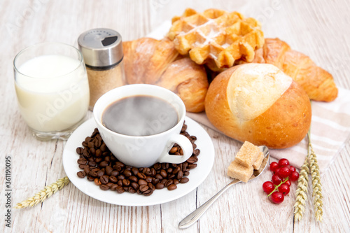 Breakfast in the morning with black coffee cup with bread with Croissant and fruit on the wooden table.