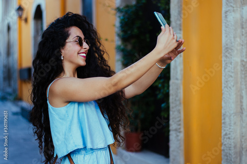 Smiling tourist woman taking photos in Spanish village in summer photo