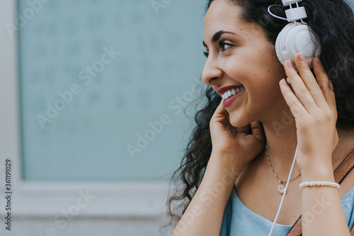 Portrait of smiling teenage girl listening to music outdoors