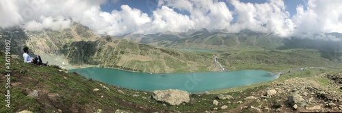 panoramic view of the mountain and lake. Boy resting on the top of mountain