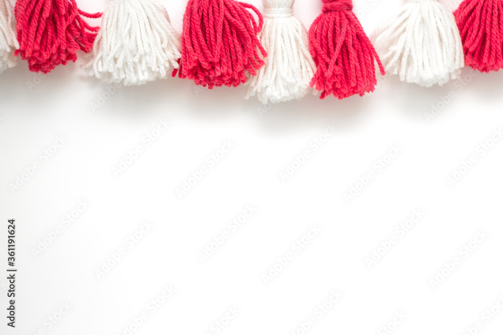 brushes from yarn of red and white color on a white background. Space for copy space. DIY yarn brushes. Garland. Garland of yarn. Pampushki from yarn. Children's creativity brushes from yarn of red and white color on a white background. Space for copy space. DIY yarn brushes. Garland. Garland of yarn. Pampushki from yarn. Children's creativity