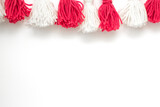 brushes from yarn of red and white color on a white background. Space for copy space. DIY yarn brushes. Garland. Garland of yarn. Pampushki from yarn. Children's creativity