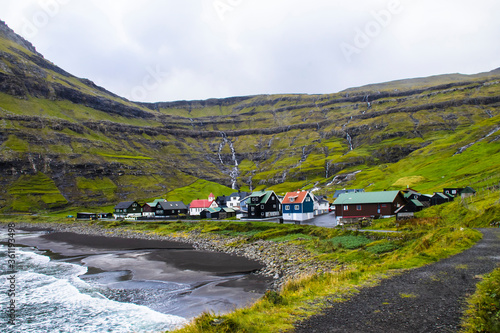 Coastal beautyful Vidareidi - colorful village on Vidoy island with tallest vertical sea cliff Cape Enniberg in the world with Villingadalsfjall peak. Faroe Islands.
