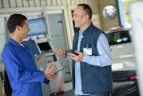 two professional mechanics talking in garage