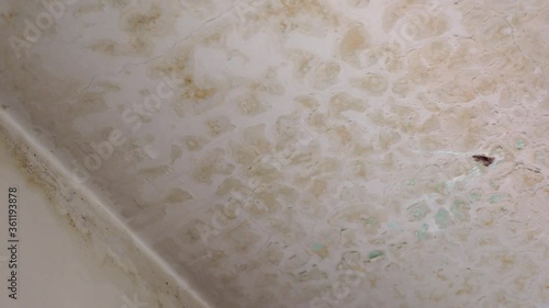 Water leakage from upper neighbors flat destroying apartment plaster ceiling, damaging surfaceand creating many dirty spots. Process of wet mold formation on the ceiling, old abandoned flat with photo