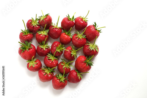 Fresh big strawberries with long stems in heart shaped form 