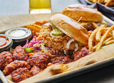 fried chicken sandwich and cheeseburger in tray with fries and boneless wings