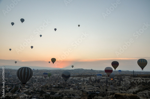 Colorful hot air balloons flying over rock and valley landscape in morning fog at sunrise in Cappadocia, Anatolia, Turkey