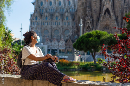Photography young and pretty tourist woman with face mask posing in front of sagrada familia