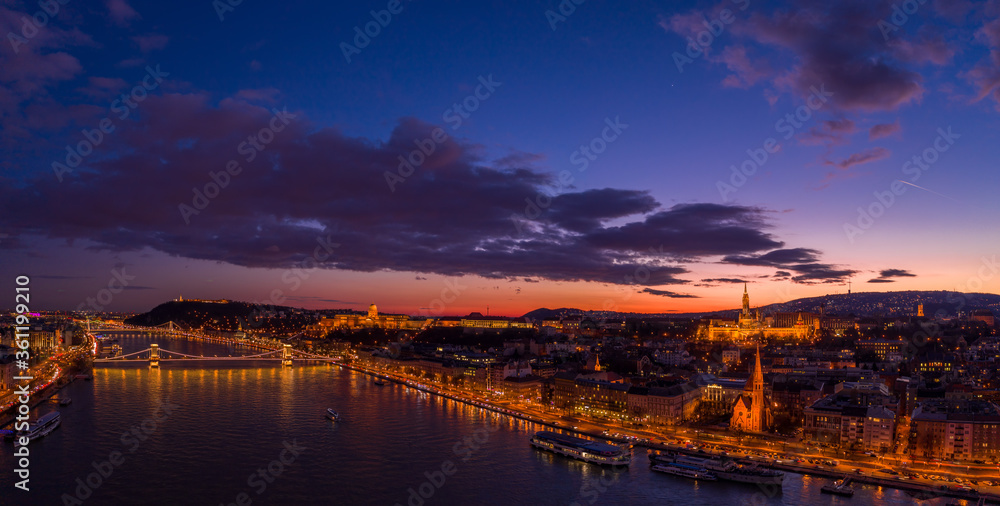 Panoramic aerial drone of lighted Matthias Church on Buda Hill by Danube river during Budapest sunset