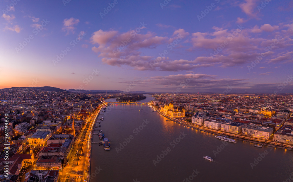 Aerial drone shot of Danube river with lighted quai with purple sky during Budapest sunset