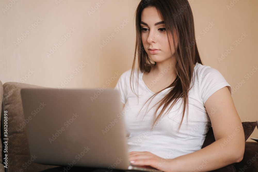 Young woman work at home in quarantine. Woman use laptop on sofa. Woman study distance learning Young woman work at home in quarantine. Woman use laptop on sofa. Woman study distance learning