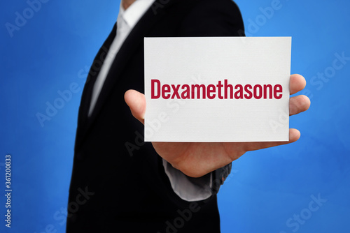 Dexamethasone. Lawyer holding a card in his hand. Text on the board presents term. Blue background. Law, justice, judgement photo