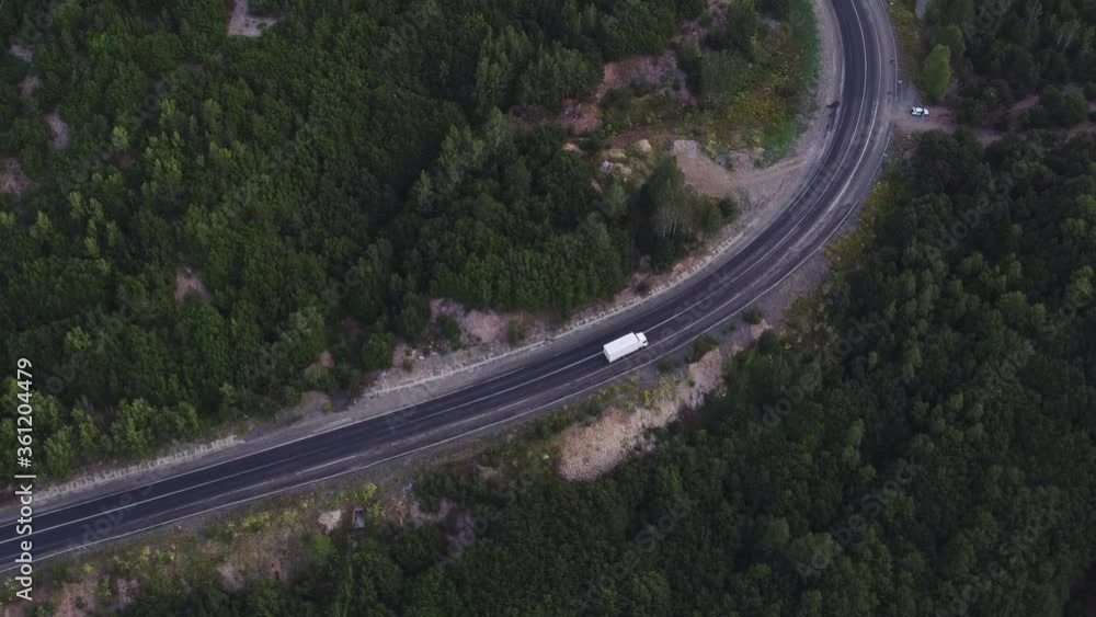 One small truck with white trailer and cab driving / traveling alone on serpentine asphalt empty road, freeway top down view follow vehicle aerial footage / Freeway trucks traffic One small truck with white trailer and cab driving / traveling alone on serpentine asphalt empty road, freeway top down view follow vehicle aerial footage / Freeway trucks traffic