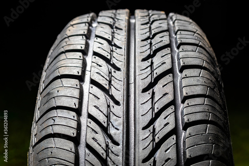 Car tire in dark color. Night shooting. The tread is summer. Light falls from above.